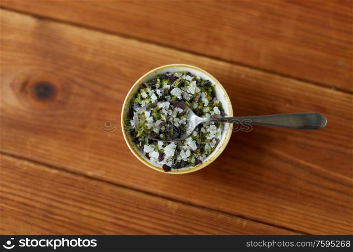 food, culinary and unhealthy eating concept - close up of flavored sea salt in bowl with spoon on wooden table. close up of flavored sea salt in bowl with spoon