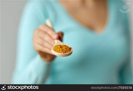 food, culinary and unhealthy eating concept - close up of woman with curry on wooden spoon. close up of woman with curry on wooden spoon