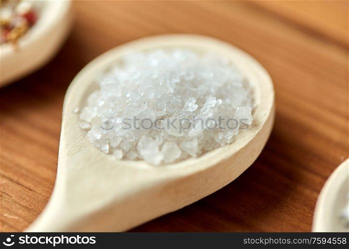 food, culinary and unhealthy eating concept - close up of wooden spoon with sea salt. close up of wooden spoon with sea salt