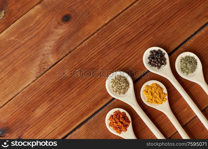 food, culinary and unhealthy eating concept - spoons with different spices on wooden table. spoons with different spices on wooden table