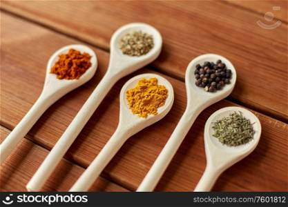 food, culinary and unhealthy eating concept - spoons with different spices on wooden table. spoons with different spices on wooden table
