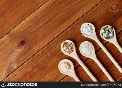 food, culinary and unhealthy eating concept - spoons with salt and spices on wooden table. spoons with salt and spices on wooden table