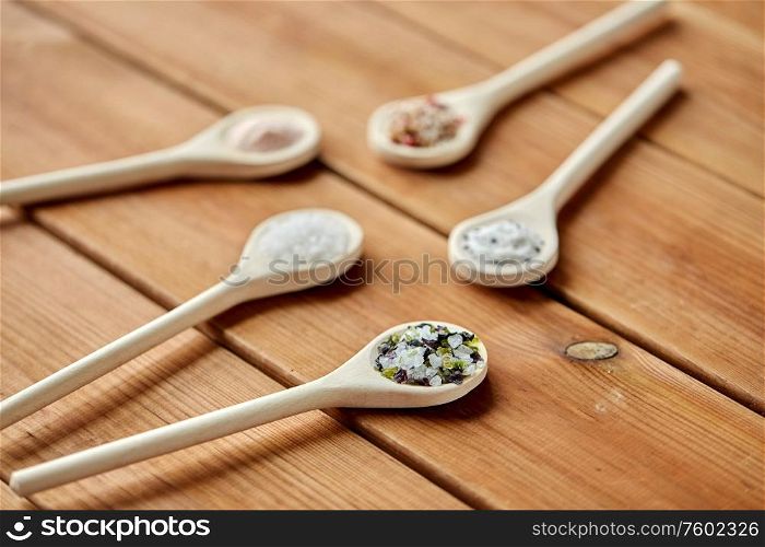 food, culinary and unhealthy eating concept - spoons with salt and spices on wooden table. spoons with salt and spices on wooden table
