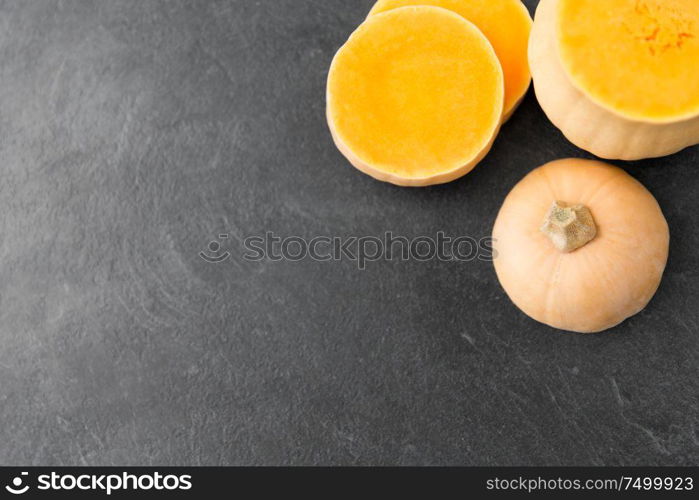 food, culinary and vegetable concept - cut pumpkin on stone background. cut pumpkin on stone background