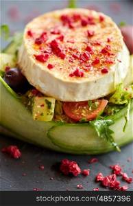 food, culinary, haute cuisine and cooking concept - close up of goat cheese salad with vegetables and dried raspberries at restaurant or cafe