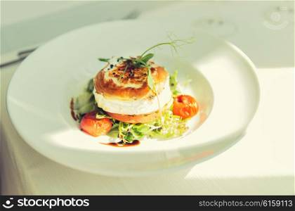 food, culinary, haute cuisine and cooking concept - close up of halloumi cheese salad with vegetables on plate at restaurant