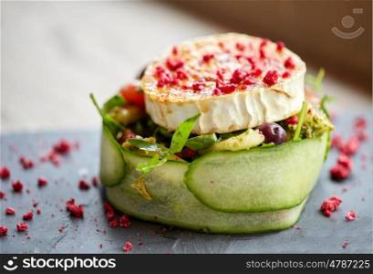 food, culinary, haute cuisine and cooking concept - goat cheese salad with vegetables and dried raspberries at restaurant or cafe
