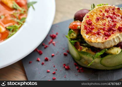 food, culinary, haute cuisine and cooking concept - goat cheese salad with vegetables and dried raspberries at restaurant or cafe