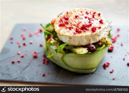 food, culinary, haute cuisine and cooking concept - goat cheese salad with vegetables and dried raspberries at restaurant or cafe. goat cheese salad with vegetables at restaurant