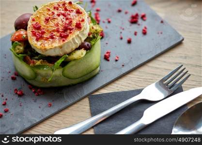 food, culinary, haute cuisine and cooking concept - goat cheese salad with vegetables and dried raspberries at restaurant or cafe. goat cheese salad with vegetables at restaurant