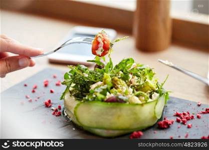 food, culinary, haute cuisine and people concept - woman eating cottage cheese salad with vegetables and dried raspberries at restaurant or cafe