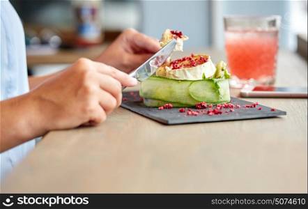 food, culinary, haute cuisine and people concept - woman eating goat cheese salad with vegetables and dried raspberries using fork and knife at restaurant or cafe. woman eating goat cheese salad at restaurant