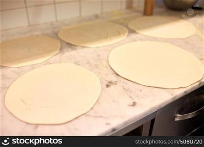 food, culinary, italian kitchen and cooking concept - raw pizza dough on table at pizzeria. raw pizza dough on table at pizzeria
