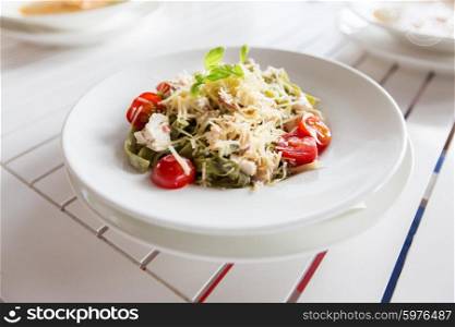 food, culinary, italian kitchen and eating concept - close up of pasta with tomato and cheese on plate at restaurant