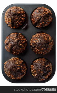 Food: dark chocolate muffins with roasted peanuts in baking pan, isolated on white background
