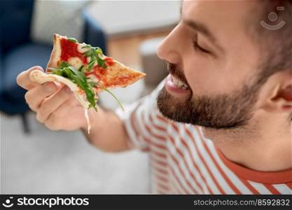 food delivery, consumption and people concept - close up of happy man eating takeaway pizza at home. happy man eating takeaway pizza at home