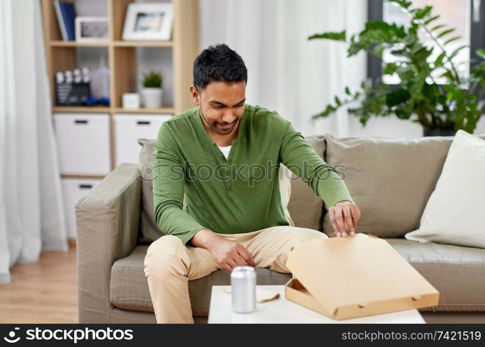 food delivery, consumption and people concept - excited indian man looking inside of takeaway pizza box at home. indian man looking inside of takeaway pizza box