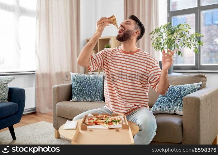 food delivery, consumption and people concept - happy man eating takeaway pizza at home. happy man eating takeaway pizza at home