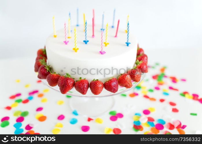 food, dessert and party concept - close up of birthday cake with candles and strawberries on stand. close up of birthday cake with candles on stand