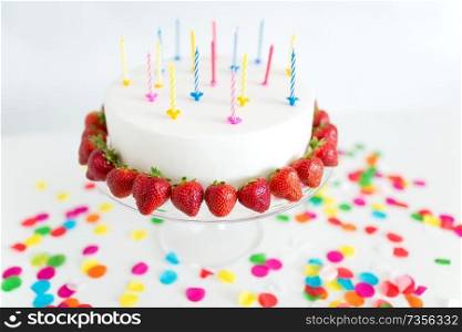 food, dessert and party concept - close up of birthday cake with candles and strawberries on stand. close up of birthday cake with candles on stand