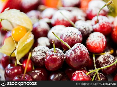 food, dessert and summer concept - close up of dish with sugared fruits or cherries