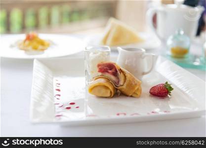 food, dessert, morning and eating concept - close up of plate with pancakes and honey or jam on table