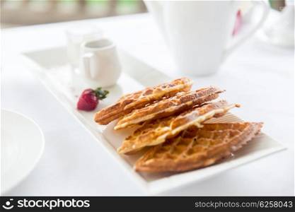 food, dessert, morning and eating concept - close up of waffles on plate at breakfast on table