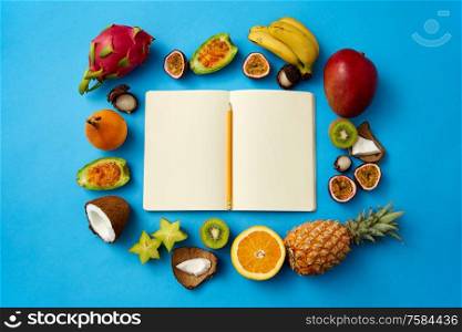 food, diet and healthy eating concept - different exotic fruits around notebook or diary with pencil and empty pages on blue background. exotic fruits around notebook with empty pages