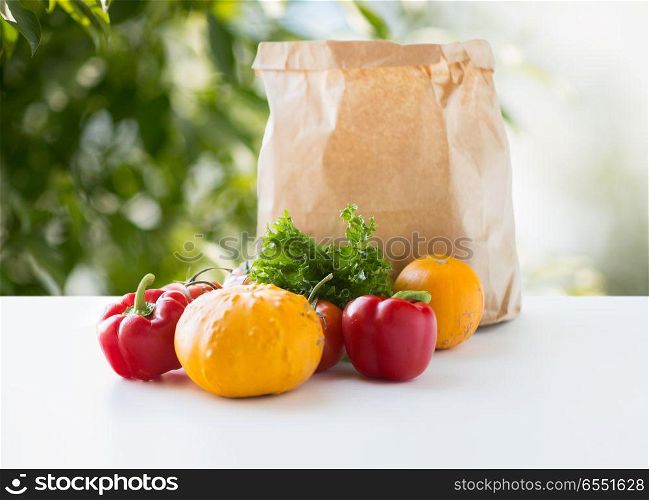 food, diet and healthy eating concept - paper bag with fresh vegetables on table over green natural background. paper bag with vegetable food on table. paper bag with vegetable food on table