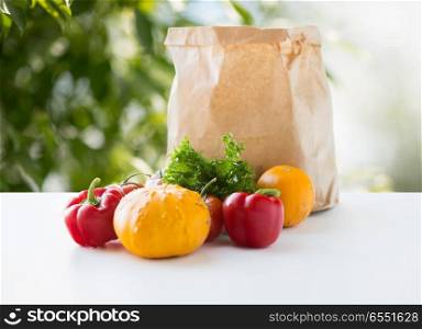 food, diet and healthy eating concept - paper bag with fresh vegetables on table over green natural background. paper bag with vegetable food on table. paper bag with vegetable food on table