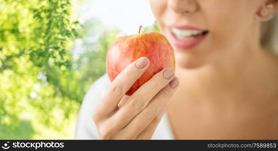 food, diet and people concept - close up of woman holding ripe red apple over green natural background. close up of woman holding ripe red apple