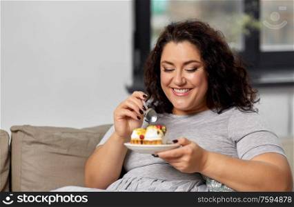 food, diet and people concept - happy smiling young woman eating cake at home. smiling young woman eating cake at home