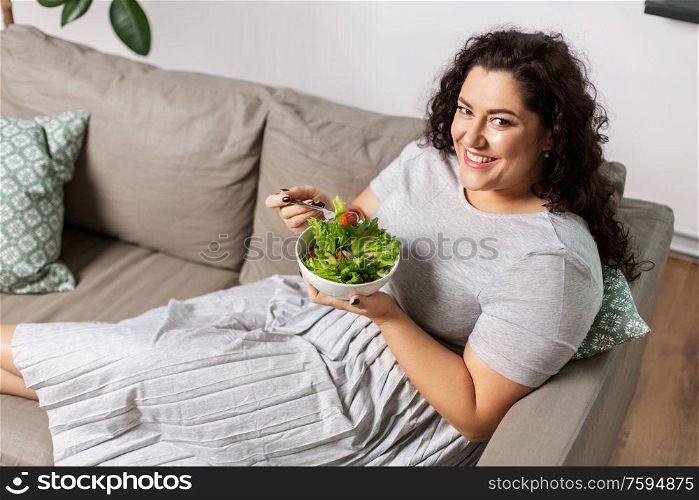 food, diet and people concept - happy smiling young woman eating vegetable salad at home. smiling young woman eating vegetable salad at home