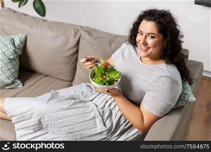 food, diet and people concept - happy smiling young woman eating vegetable salad at home. smiling young woman eating vegetable salad at home