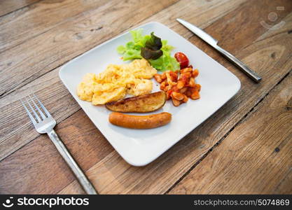 food, dinner and eating concept - scrambled eggs, sausage, chili beans and salad on plate. close up of food on plate