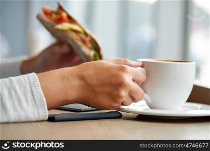 food, dinner and people concept - woman drinking coffee and eating panini sandwich for breakfast or lunch at cafe