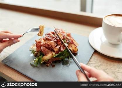 food, dinner and people concept - woman eating prosciutto ham salad on stone plate at restaurant and coffee cup on table. woman eating prosciutto ham salad at restaurant