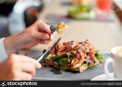 food, dinner and people concept - woman eating prosciutto ham salad on stone plate at restaurant. woman eating prosciutto ham salad at restaurant