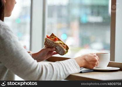 food, dinner and people concept - woman eating salmon panini sandwich with tomatoes and cheese and drinking coffee for lunch at restaurant