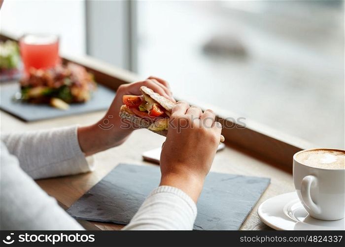 food, dinner and people concept - woman eating salmon panini sandwich with tomatoes and cheese at restaurant