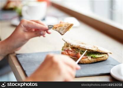 food, dinner and people concept - woman eating salmon panini sandwich with tomatoes and cheese at restaurant. woman eating salmon panini sandwich at restaurant
