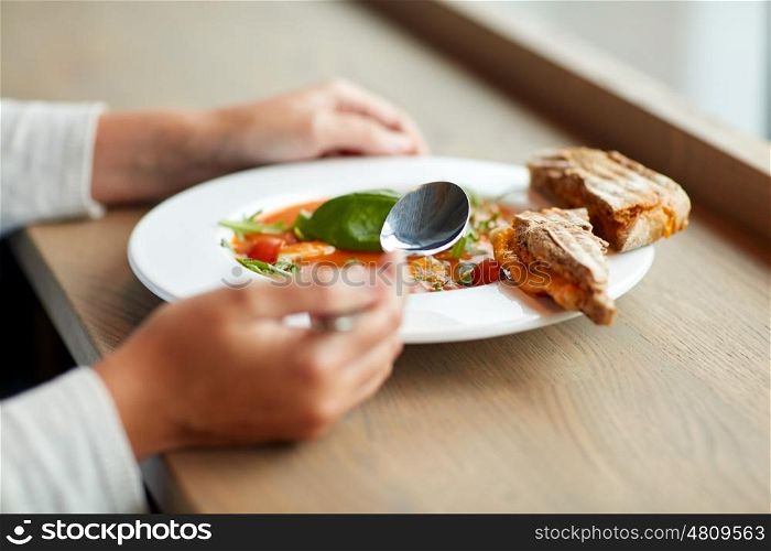 food, dinner, culinary and people concept - woman eating gazpacho soup with bread and spoon at restaurant