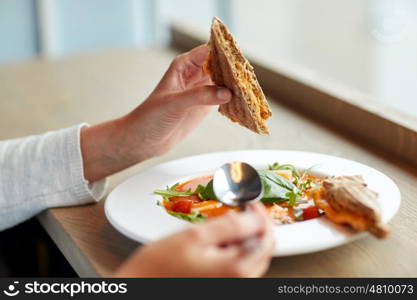 food, dinner, culinary and people concept - woman eating gazpacho soup with bread and spoon at restaurant