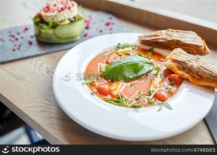 food, dinner, haute cuisine and cooking concept - plate of delicious gazpacho soup, sandwich and salad at restaurant