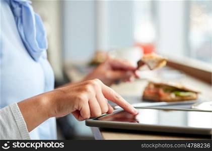 food, dinner, technology and people concept - woman with tablet pc computer eating salmon panini sandwich at restaurant