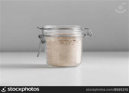 food, eating and cooking concept - jar with almond flour on white background. close up of jar with almond flour on white table