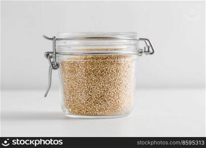 food, eating and cooking concept - jar with quinoa on white background. close up of jar with quinoa on white table
