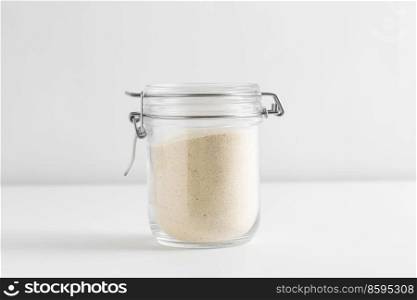 food, eating and cooking concept - jar with semolina on white background. close up of jar with semolina on white table