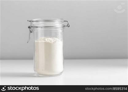 food, eating and cooking concept - jar with wheat flour on white background. close up of jar with wheat flour on white table