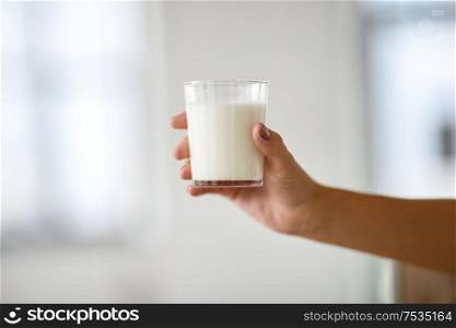 food, eating and dairy products concept - close up of female hand holding glass of milk. close up of female hand holding glass of milk